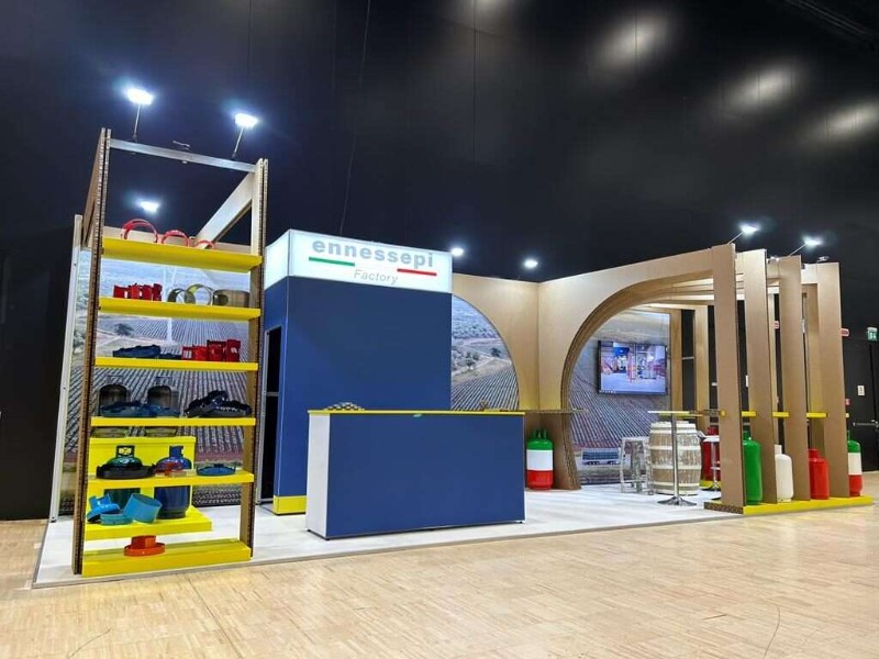 Stand Ennessepi Factory: scaffalatura gialla, torre blu e archi in legno